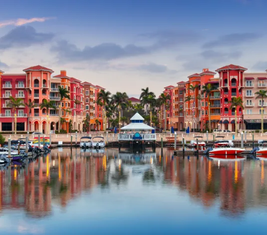 Pastel waterfront buildings and marina at dusk in Naples, Florida
